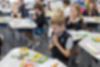 This image links to the Saint Nicholas Catholic School Tours and Open House page. The photograph depicts an elementary school student praying at his desk at Saint Nicholas School in Los Altos California