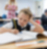 A link to the Saint Nicholas Catholic School Elementary Academics page. The image shows a boy in second grade looking at a book and working on some classwork at his desk.
