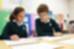 A link to the Saint Nicholas Catholic School Junior High School Academics Page. The photograph shows a middle-school aged girl and boy working on math problems.
