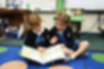This image links to the Saint Nicholas Catholic School Tuition, Fees and Assistance page. It showsTwo kindergarten students read a book together.