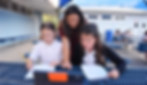 A teacher works with two fifth grade students  outside in the sunshine