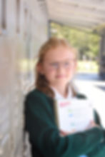 A middle-school girl, holding her math book, smiles as she leans against her locker at Saint Nicholas Catholic School in Los Altos California
