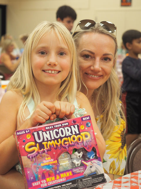 A mom sits with her daughter who just won a bingo game at St. Nicholas School's taco and 