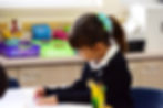 A link to the Saint Nicholas Catholic School Elementary School Academics Page. The photo shows a girl in elementary school coloring her work.