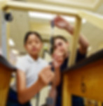 A link to the Saint Nicholas Catholic School Junior High School Academics Page. The image shows two middle school students working on a physics exeriment.